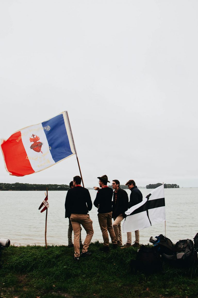 A group of young adults holding flags by the ocean, capturing an outdoor adventurous spirit.