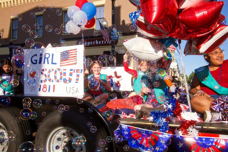 Joyful Girl Scout parade with balloons and bubbles in a vibrant street celebration.