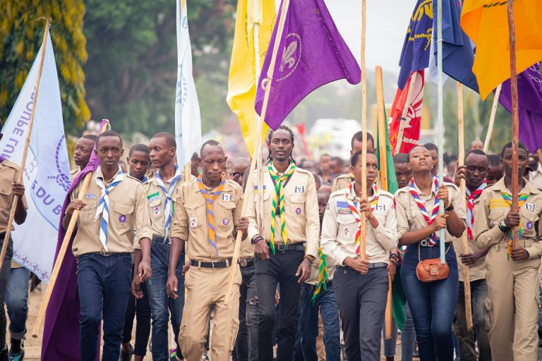 Young participants in uniform marching with flags in an outdoor rally event.